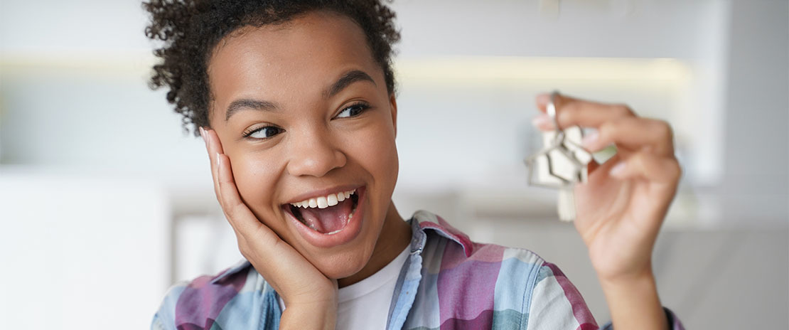 Menina negra feliz com um objeto desfocado e não identificável na mão.