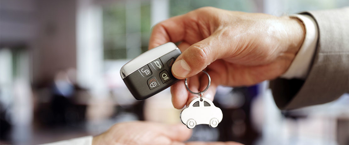 Pessoa entrega uma chave de carro para outra.