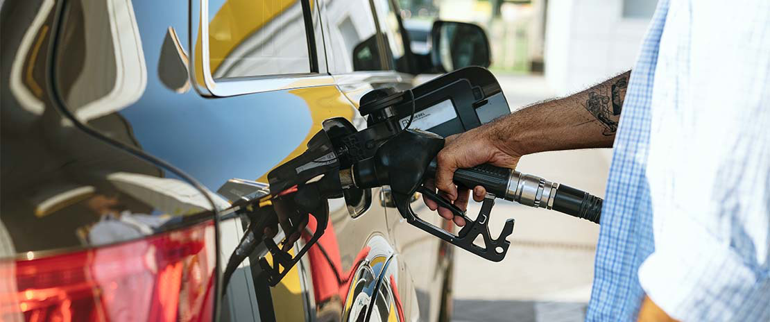 Pessoa em punhando uma bomba de gasolina enchendo o tanque de alguém.