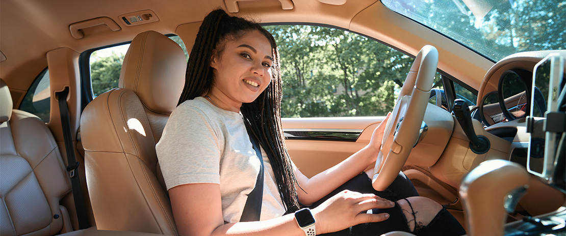 Mulher negra dentro de um carro luxuoso.